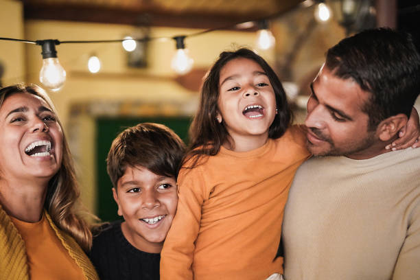 happy family laughing and hugging each other at home outdoor on patio - latin parents with children love concept - latin american imagens e fotografias de stock