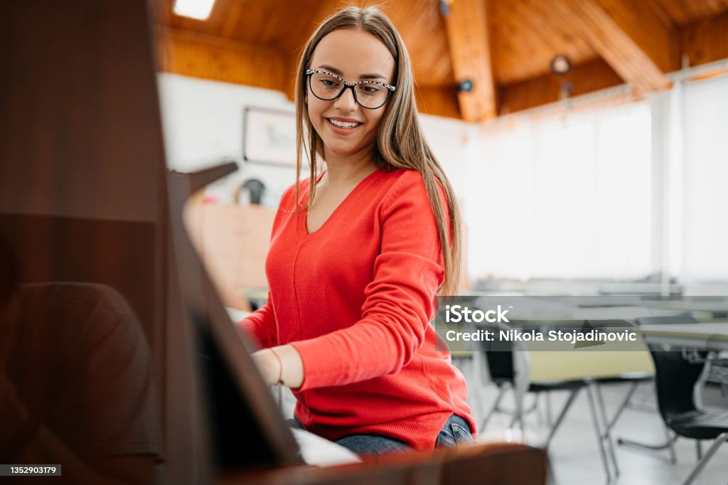 A woman plays the piano at school Musical Instrument Stock Photo