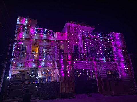 Stock photo showing close-up view of house decorated with white and pink coloured fairy lights for Indian traditional festival of lights, Diwali like Christmas.