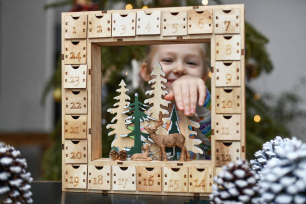 una niña abre el calendario de adviento de madera con regalos - advent calendar advent christmas childhood fotografías e imágenes de stock