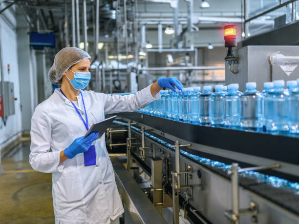 istock Technologist in bottling factory checking water bottles before shipment. 1352904380