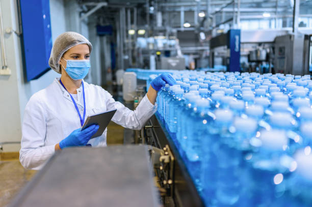 istock Technologist in bottling factory checking water bottles before shipment. 1352904764