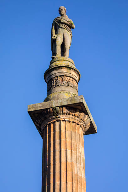 The centre of the Scottish town of Elgin on an early summer's day. The Grecian columned St Giles Church dominates the space, with the war memorial, a bronze statue depicting an heroic figure of victory and peace, adding interest to the cobbled streets.