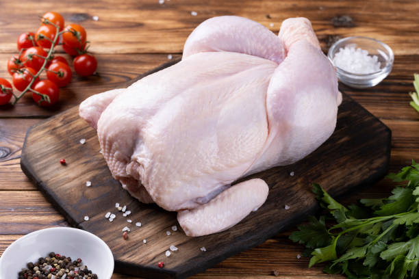 whole raw chicken on a wooden board