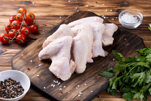 istock Raw chicken wings on wooden cutting board 1352905985
