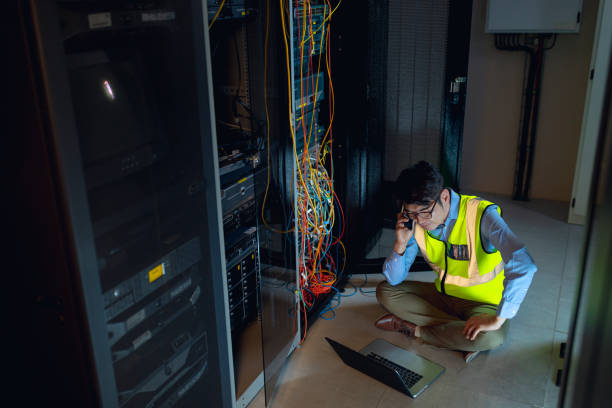 istock Asian male engineer with laptop talking on smartphone while inspecting in computer server room 1352906472