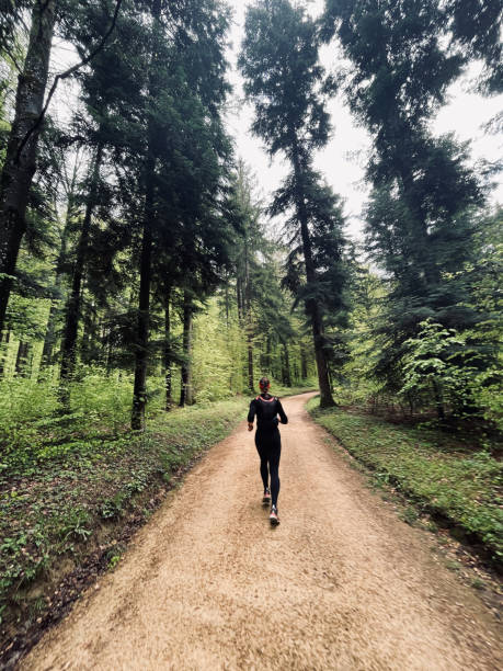 giovane donna corre attraverso una foresta lussureggiante - journey footpath exercising effort foto e immagini stock