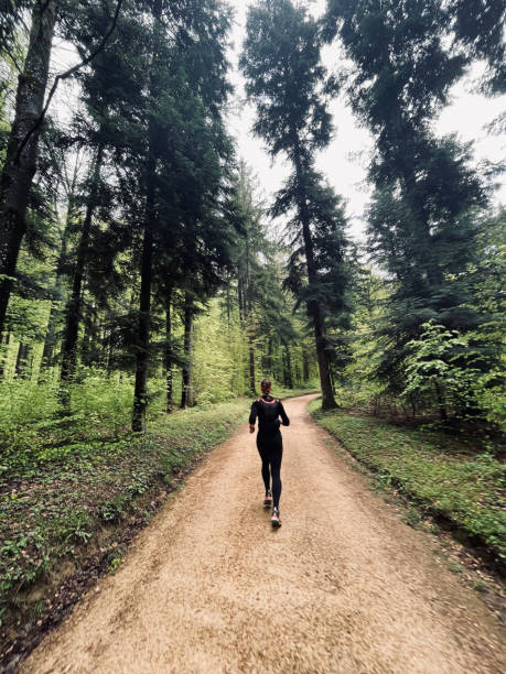молодая женщина бежит по пышному лесу - journey footpath exercising effort стоковые фото и изображения