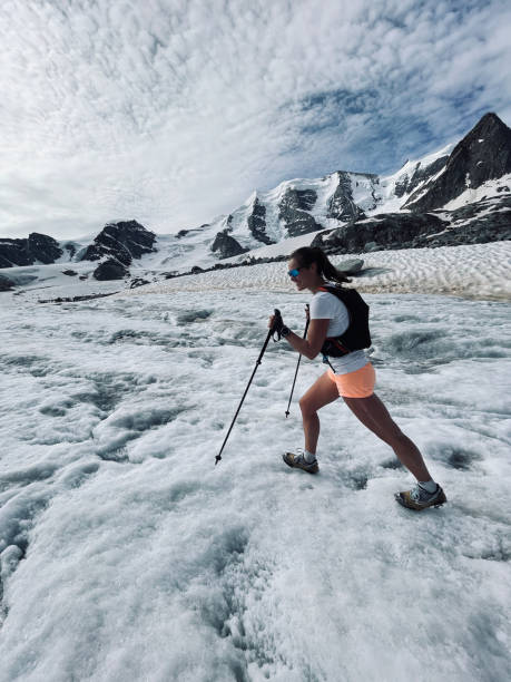 young woman runs with poles and crampons across glacier - on top of mountain peak success cold imagens e fotografias de stock