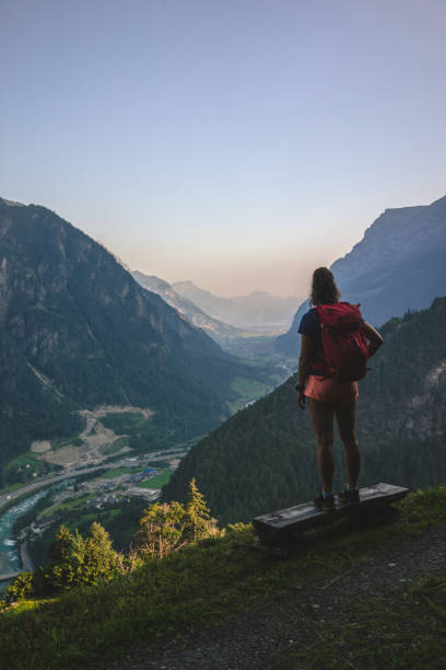 istock Backpacker stands on bench above a mountain valley 1352906620