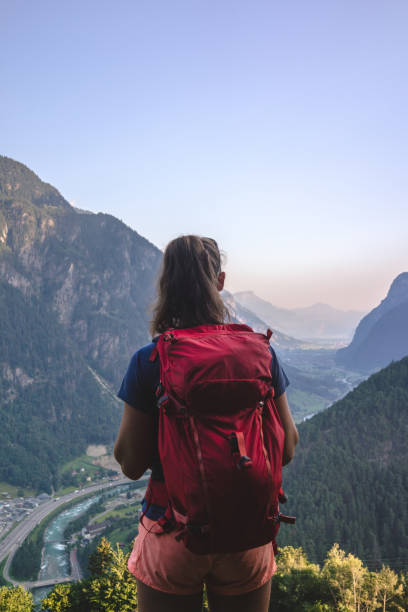 istock Backpacker stands on bench above a mountain valley 1352906649