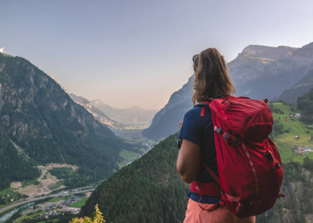 istock Backpacker stands on bench above a mountain valley 1352906651
