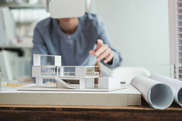 азиатская женщина-архитектор носит гарнитуру виртуальной реальности для детализации проекта модели дома. - computer engineer blueprint architect стоковые фото и изображения