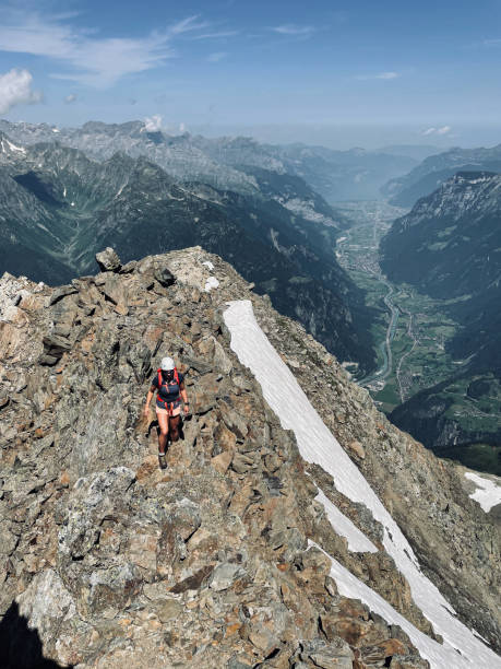 istock Woman climbs rocky mountain ridge 1352906734