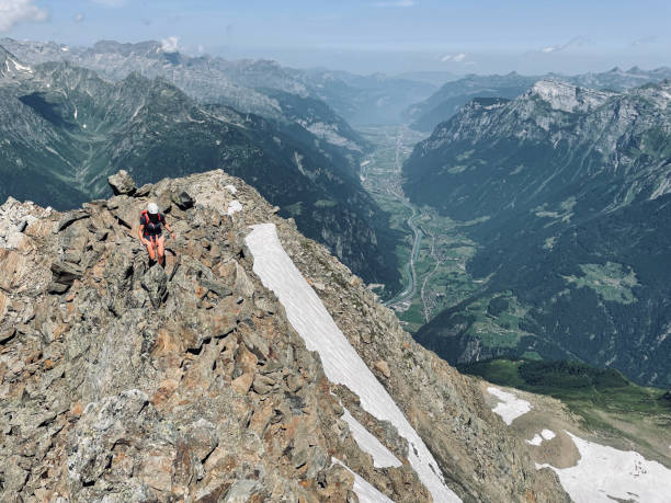 istock Woman climbs rocky mountain ridge 1352906735