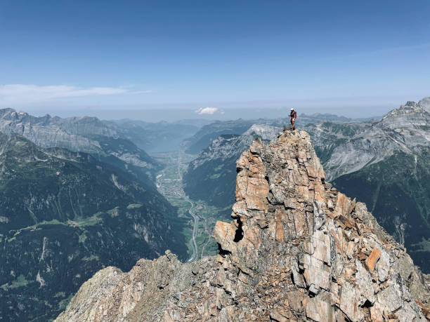 istock Woman climbs rocky mountain ridge 1352906770