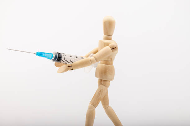 istock Wooden mannequin hold syringe. Vaccination concept. Fighting coronavirus. 1352907633