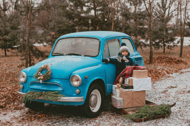istock child Decorated with a blue retro car with festive Christmas tree branches, gift boxes in craft wrapping paper, a wreath of pine fir needles. 1352910207