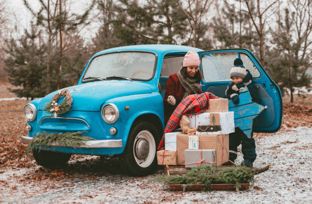 istock child Decorated with a blue retro car with festive Christmas tree branches, gift boxes in craft wrapping paper, a wreath of pine fir needles. 1352910338