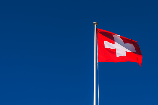 Swiss flag waving in the wind on a sunny day with blue sky