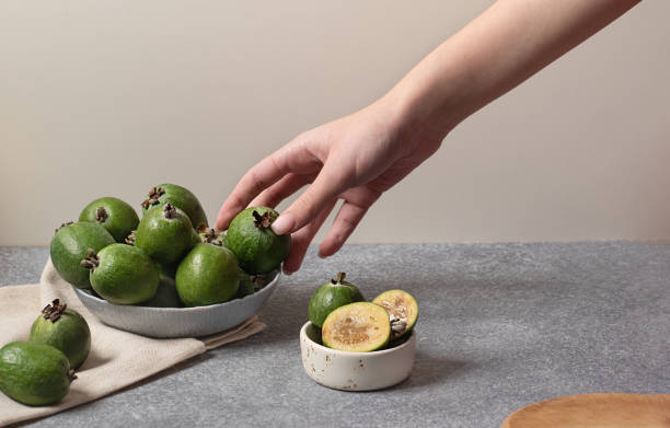 concept of limiting the amount of food. Person holding one feijoa berry concept of limiting the amount of food. Person holding one feijoa berry in gray bowl pineapple guava stock pictures, royalty-free photos & images