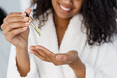 Young african american woman holding pipette with serum oil