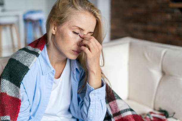 Tired woman with closed eyes touching nose bridge Fatigue and upset woman touching nose bridge feeling eye strain or headache, trying to relieve pain. Sick and exhausted female spending day at home. Depressed lady feeling weary dizzy h1n1 flu virus stock pictures, royalty-free photos & images