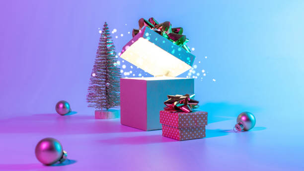 istock Neon xmas winter background. Open Christmas gift box with shine lights, minimal tree. Holiday decoration bauble ball on neon abstract gradient backdrop. Happy new year copy space. 1352923655
