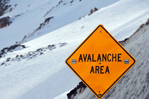 Avalanche sign against snow covered slope Loveland Pass, Colorado, USA: avalanche area danger sign - foldable yellow diamond road sign - continental divide avalanche stock pictures, royalty-free photos & images