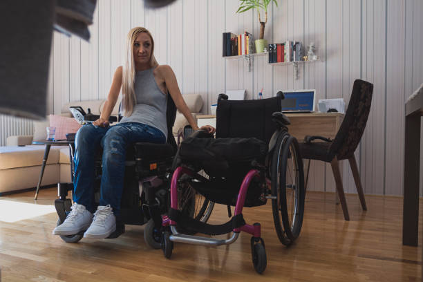 Beautiful young disabled woman in wheelchair  in her apartment stock photo