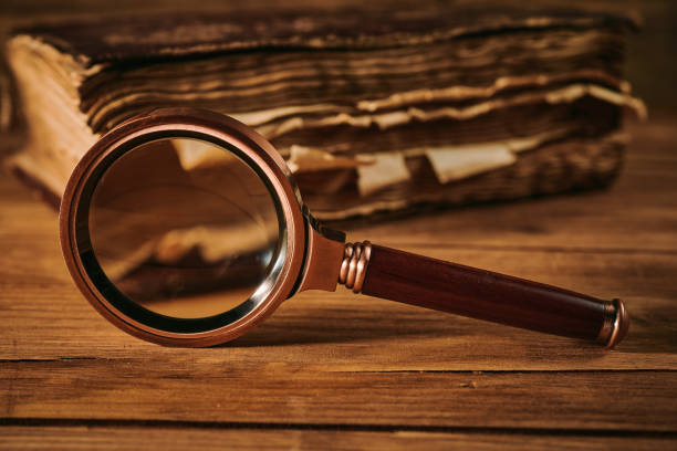 istock Magnifying glass and the ancient magic book on wooden table 1352926871
