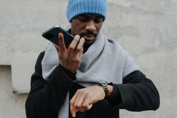 istock Busy black man outdoors talking on a loud speaker while checking his wristwatch 1352927556