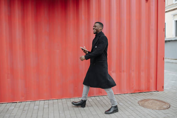istock Overjoyed black man in a warm coat walking in front of corrugated wall 1352927567