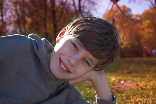 Happy little boy lying on the grass in the autumn park. A sunny day in the autumn park.