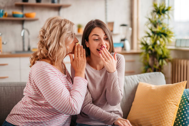 istock Mother telling secret to surprised daughter 1352928744