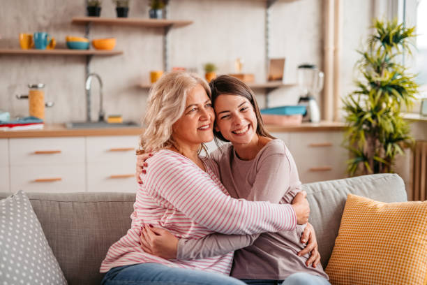 istock Mother and her grown up daughter embracing on sofa 1352929722