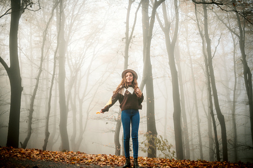 Woman walking on road at foggy autumn forest