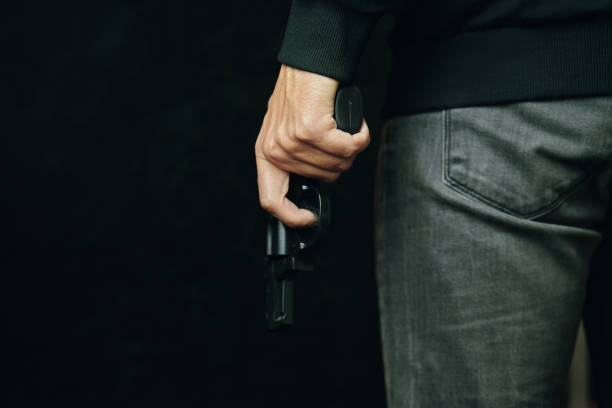 istock Man in dark clothing is holding gun. 1352937781