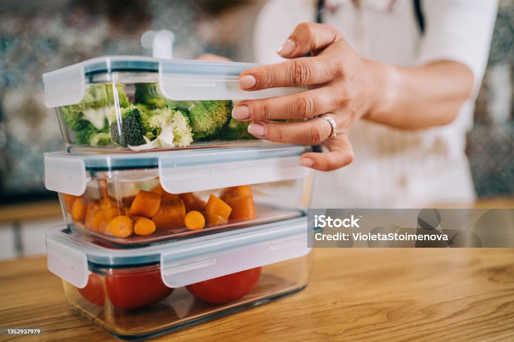 Vegetable storage. Close-up shot of female hands holding glass containers with fresh raw vegetables. Preparing Food Stock Photo
