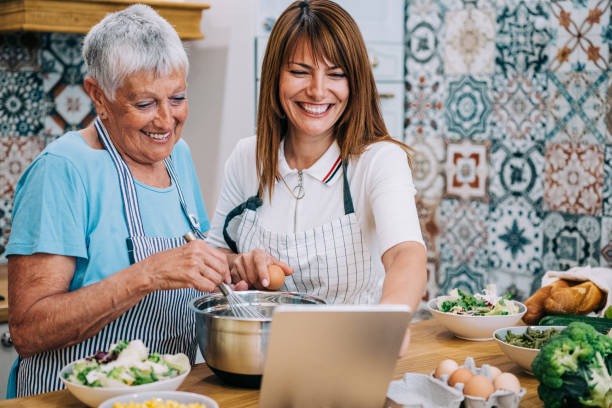 istock Mother and daughter watching recipe on digital tablet while cooking lunch in modern kitchen. 1352938048