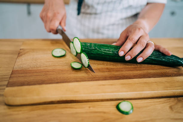 istock Female hands chopping cucumber on a cutting board. 1352938074
