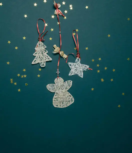 Handmade Christmas tree decorations made of threads on an emerald background with shiny stars