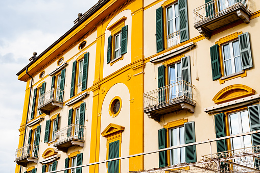 Colorful facade of the house with shutters and small balconies. Varenna, Como, Italy. High quality photo