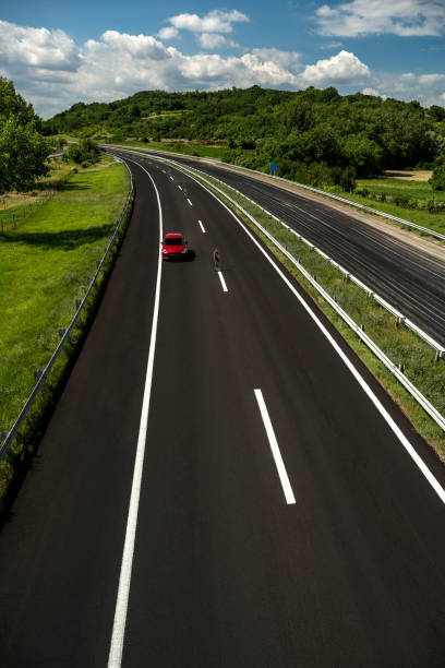 Red car driving along highway.
