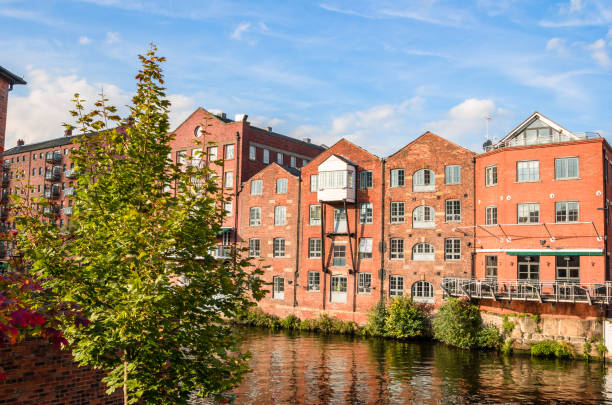 Renovated brick buildings along a river on a clear autumn day Row of old brick warehouses converted in lofts along a river on a sunny autumn day. Leeds, UK. leeds photos stock pictures, royalty-free photos & images
