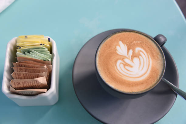 cibo - primo piano di grande formato di un caffè cappuccino con bella schiuma d'arte. - sugar sachet foto e immagini stock