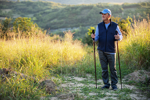 senior man taking a walk with Nordic poles in a beautiful rural area