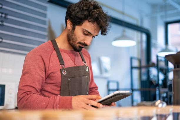 istock Young barista man using tablet in coffee shop 1352952951