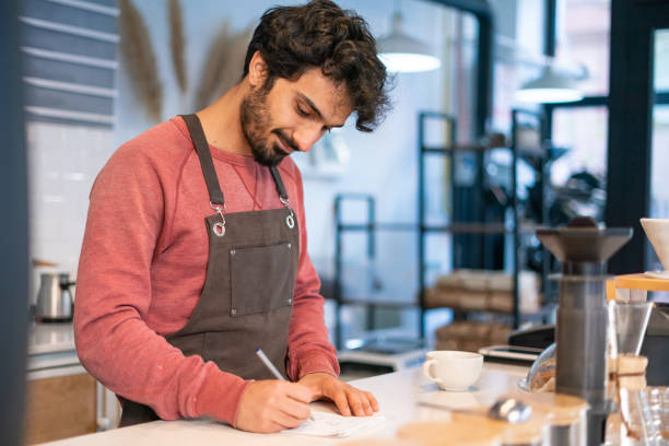 istock Young barista man taking notes in coffee shop. 1352952965