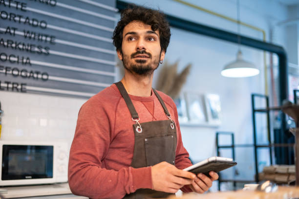 istock Young barista man using tablet in coffee shop 1352952984